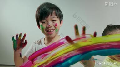 小男孩和小女孩用涂满颜料的手<strong>画画</strong>